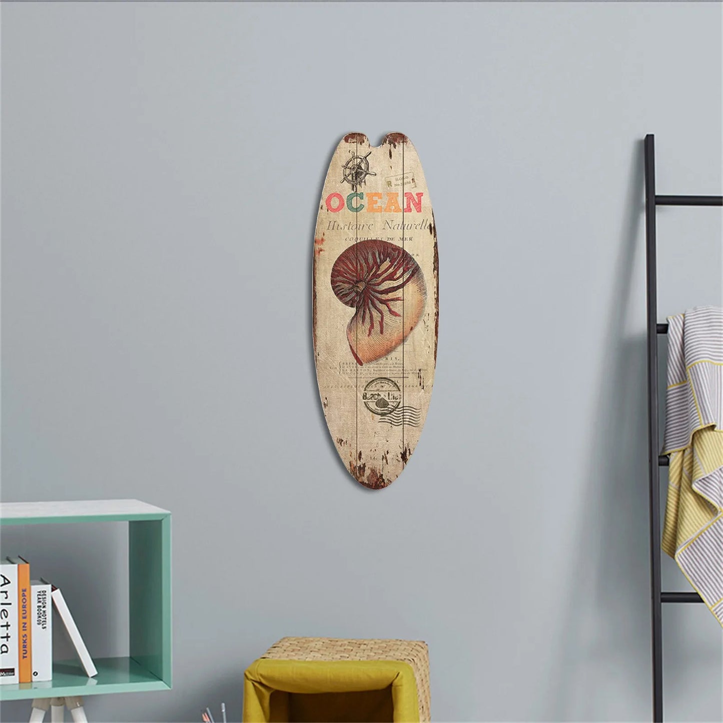 Decorative surfboard with shell design and 'Ocean' text on a gray wall.