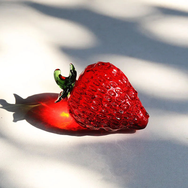 Glass strawberry on a white surface with shadows