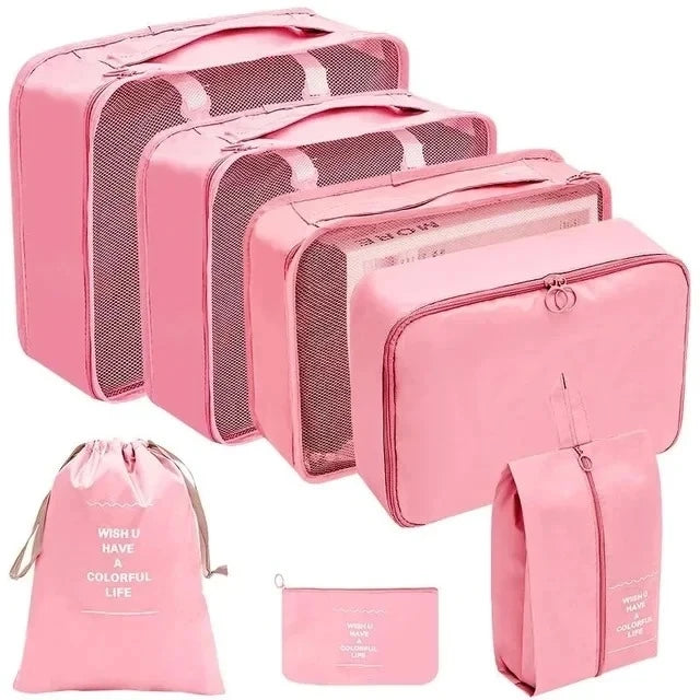 Set of pink travel packing cubes with a drawstring bag and pouch on a white background