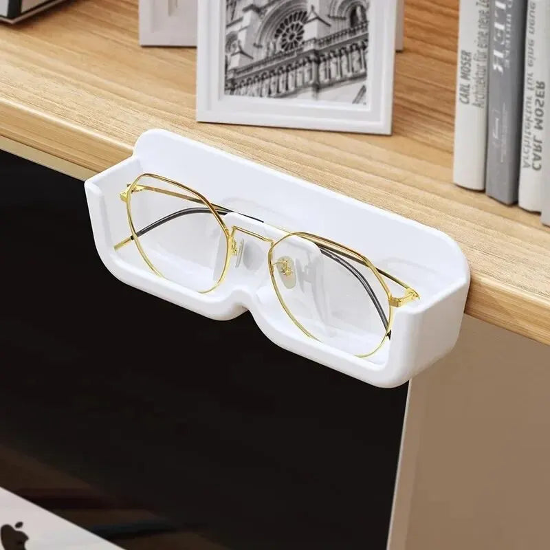 White glasses case with gold-framed glasses on a wooden surface.