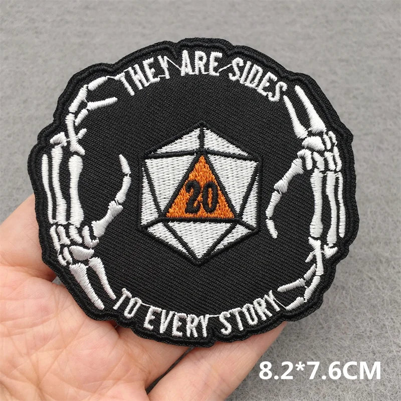 Patch with skeleton hands holding a D20 die and text on a gray background