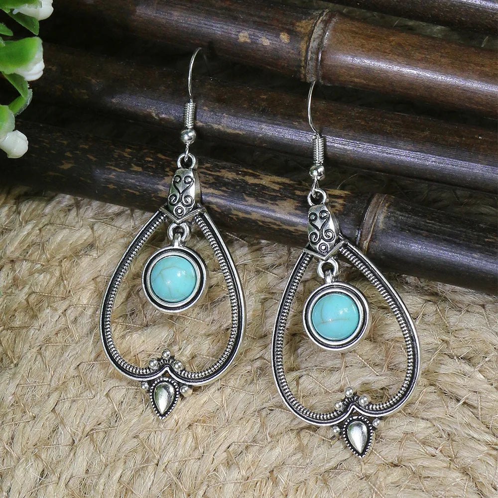 Pair of silver earrings with turquoise stones on a natural fiber background