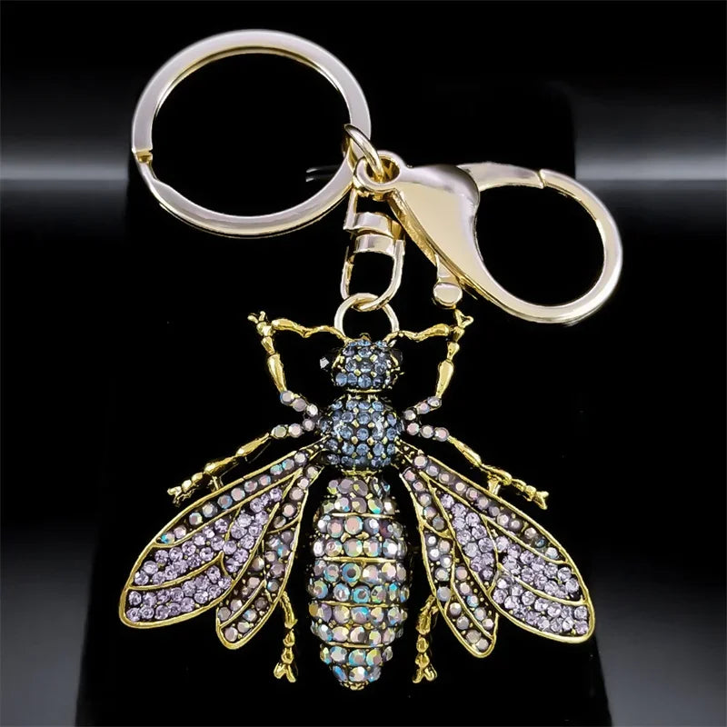 Gold bee-shaped keychain with gemstones on a black background