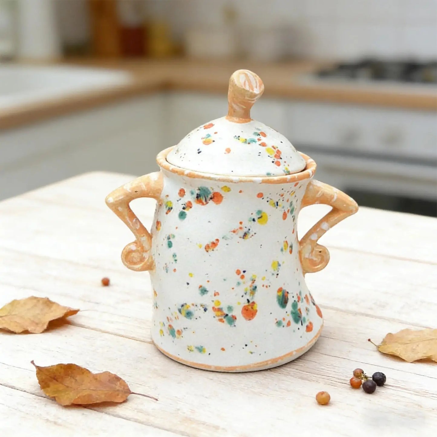 Decorative ceramic jar with colorful speckles on a wooden surface