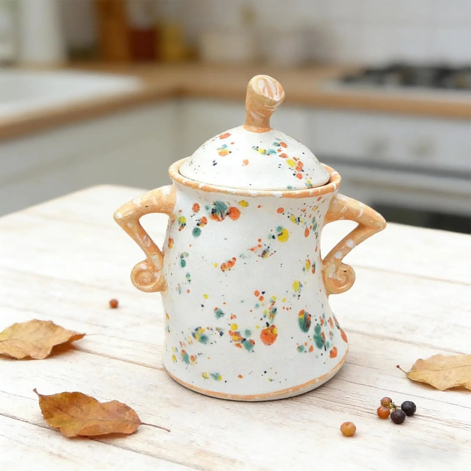 Decorative ceramic jar with colorful speckles on a wooden surface