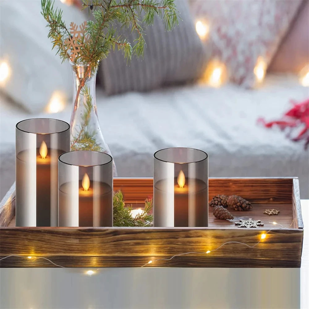 Decorative setup with candles and a vase on a wooden tray in a cozy indoor setting.