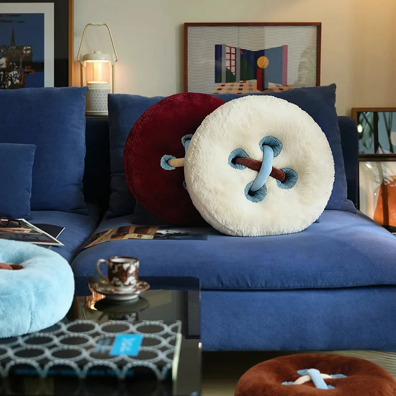 Oversized round button cushion pillows in plush fabric styled on modern blue sofa in Nordic living room interior