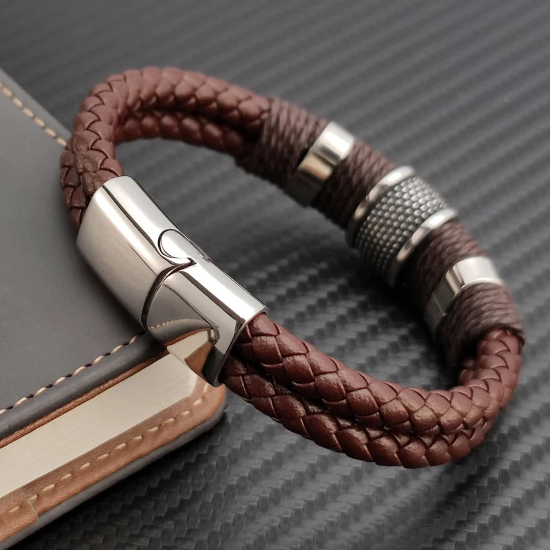 Brown braided leather bracelet with silver clasp on a textured surface