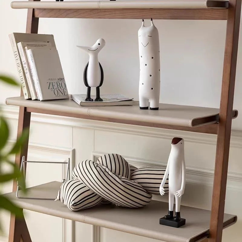 Wooden shelf with decorative items including books, a sculpture, and striped cushions.