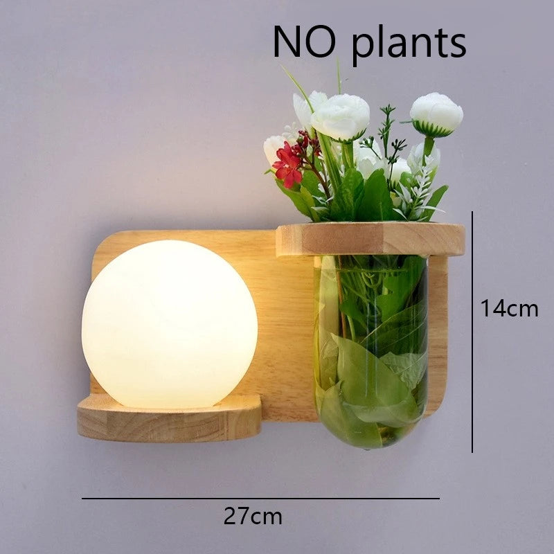 Wall-mounted lamp with a small plant holder containing flowers and a vase on a gray background.