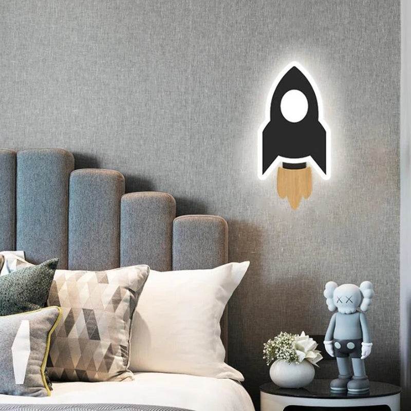 Rocket-shaped wall light on a gray wall above a bed with decorative pillows and a small figurine.