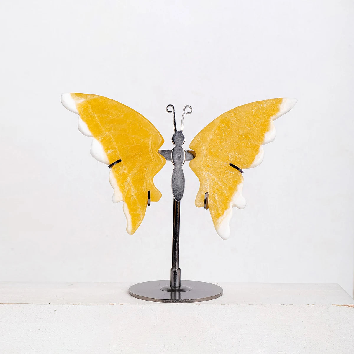 Butterfly-shaped object with yellow wings on a stand against a white background