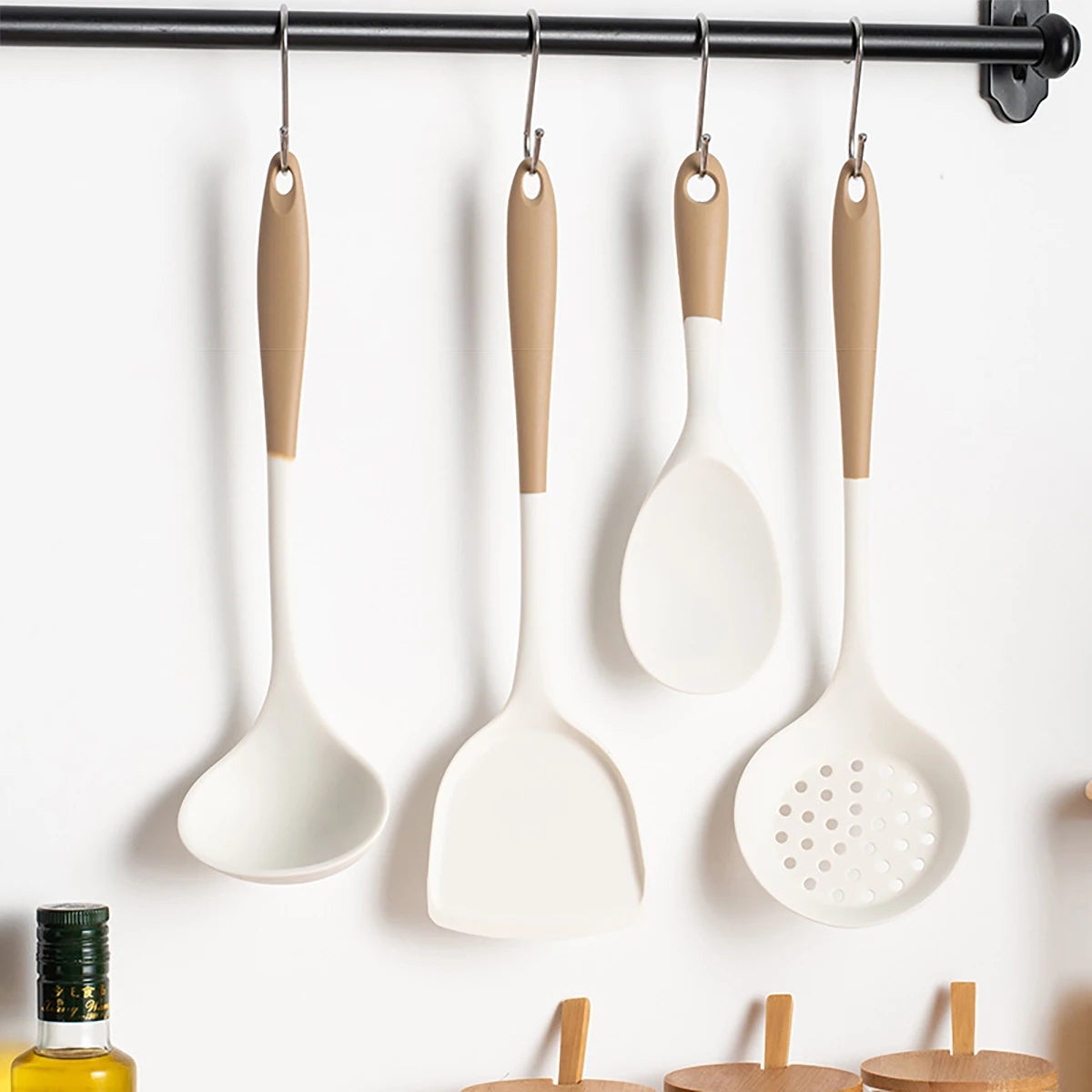 Set of white kitchen utensils with beige handles hanging on a rack.