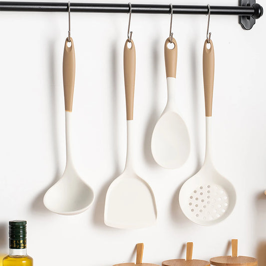Set of white kitchen utensils with beige handles hanging on a rack.