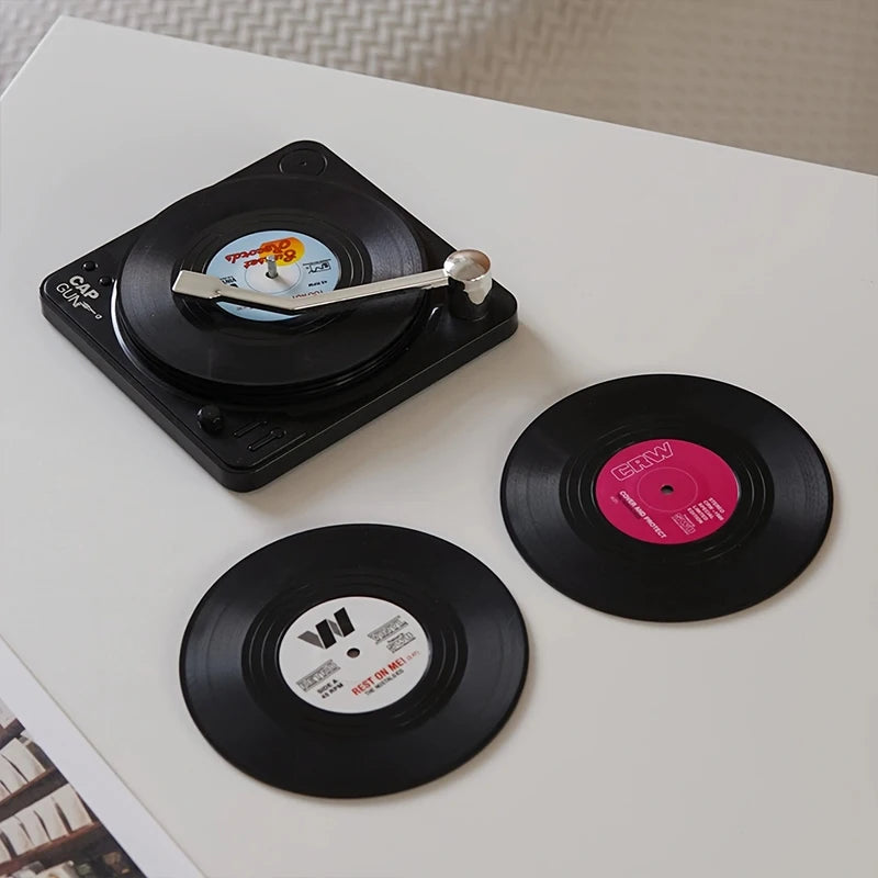 Small turntable with vinyl record coasters on a white surface