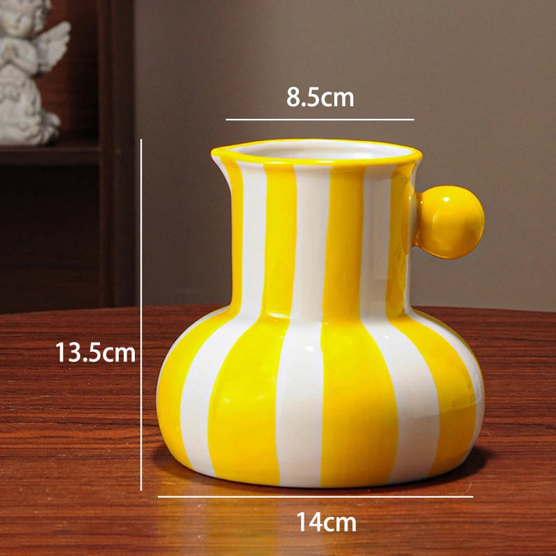 Yellow and white striped ceramic vase with measurements on a wooden surface