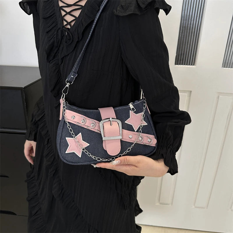 Person holding a denim handbag with pink accents and star designs.