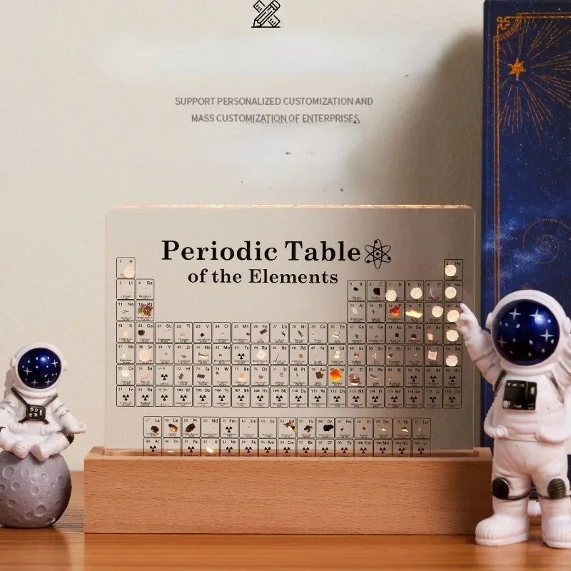 Periodic Table of Elements display with astronaut figurines on a wooden base.