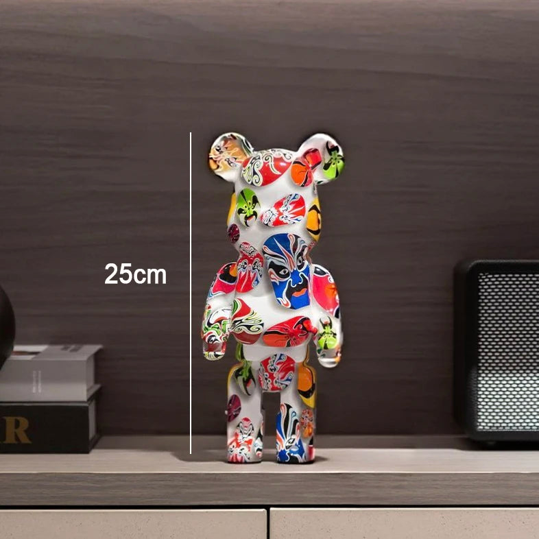 A multicolor graffiti-patterned bear figurine standing on a shelf, with a vertical measurement line and text reading 25cm indicating its height. The background shows a dark wood wall and shelf with some decorative objects.