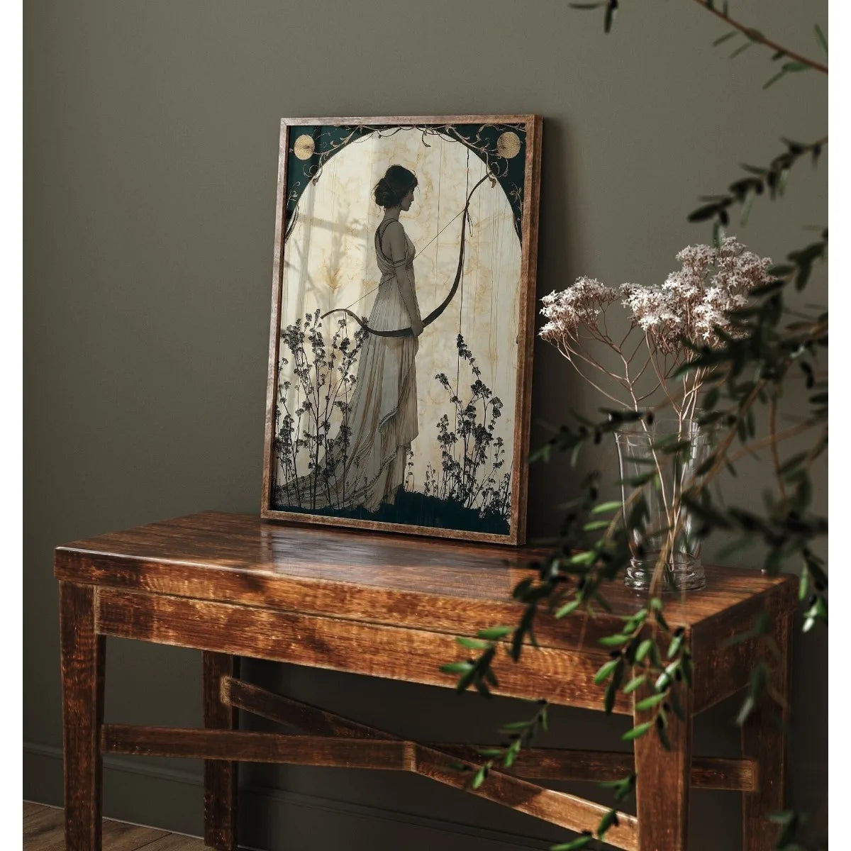 Framed artwork of a woman holding a bow on a wooden table against a dark wall.