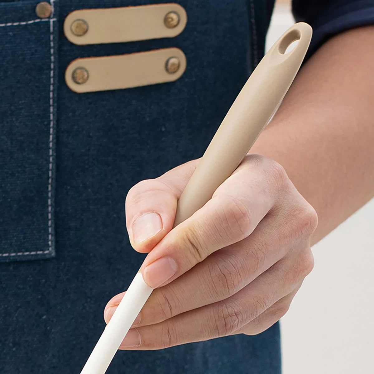 Hand holding a beige silicone utensil 