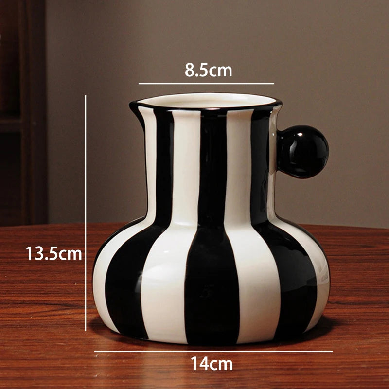 Black and white striped ceramic vase with measurements on a wooden surface