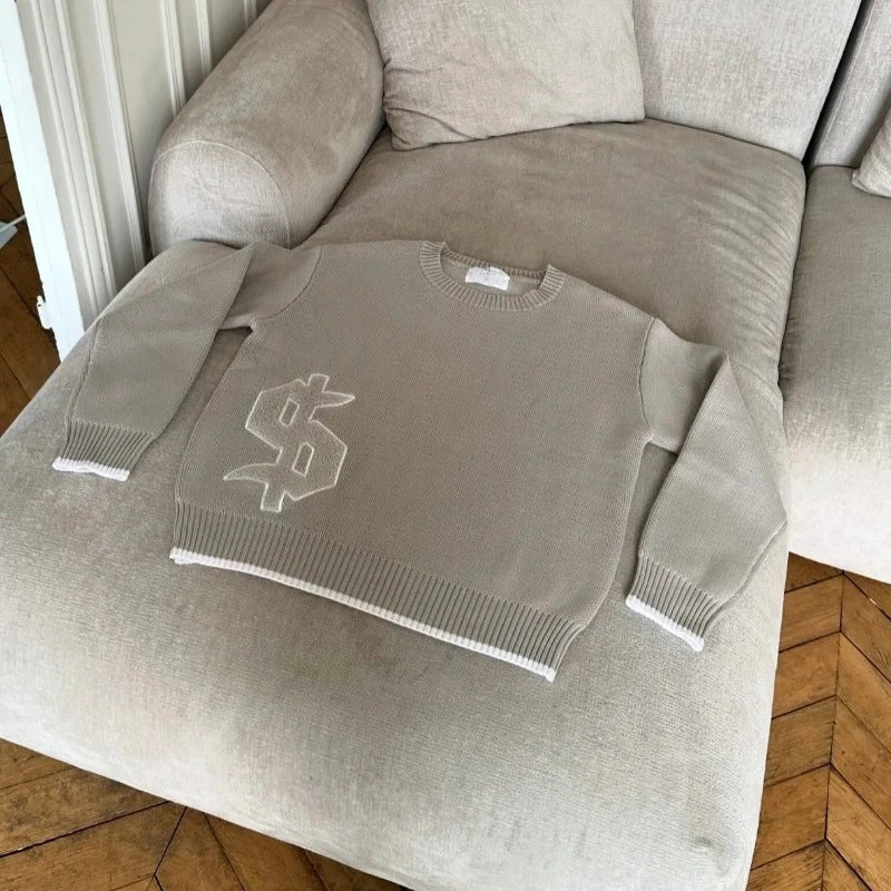 Gray sweater with a logo on a beige armchair