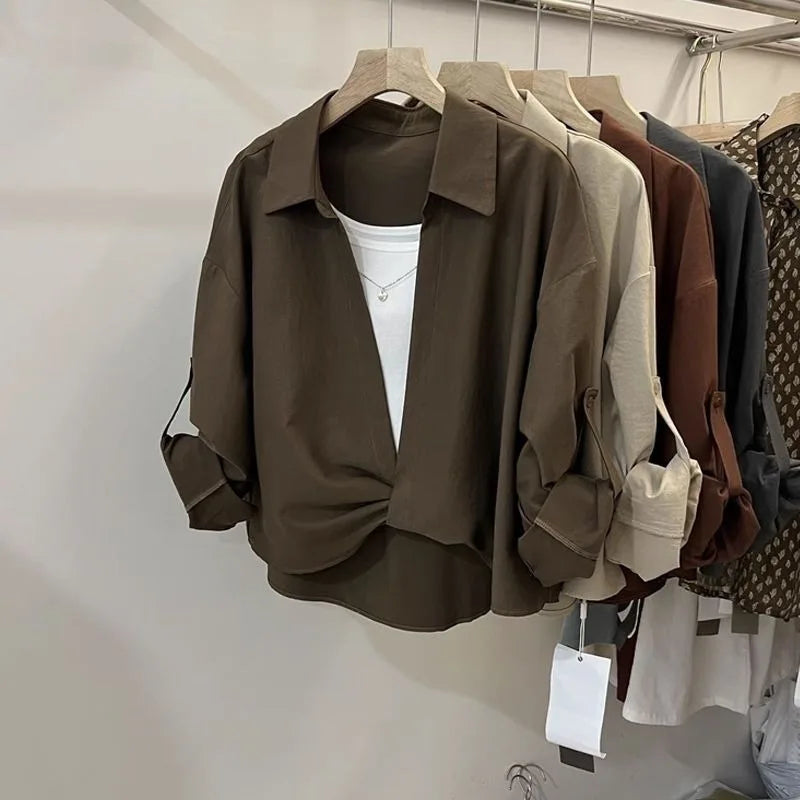 Women’s loose fit layered look blouse with long sleeves and collared neckline in neutral colours on a clothing rack