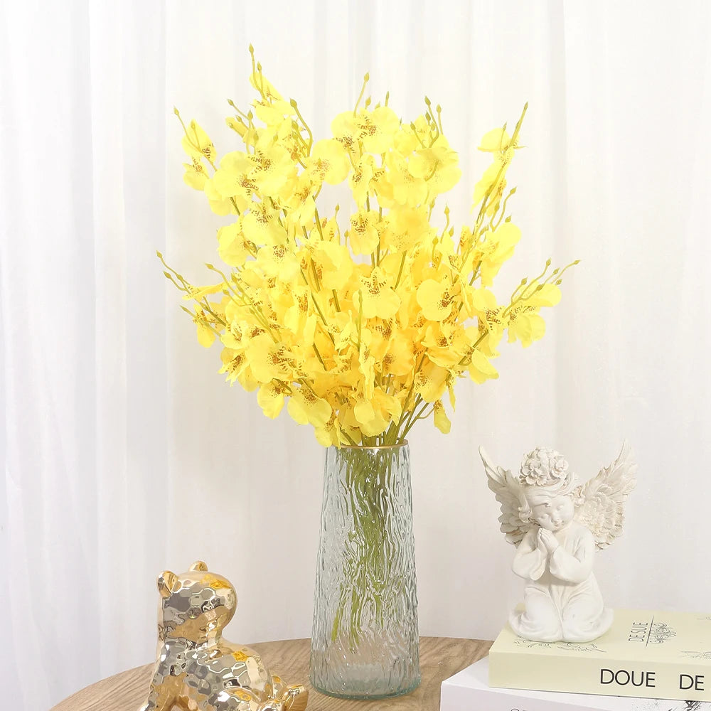 Clear glass vase with yellow flowers on a table against a white curtain background