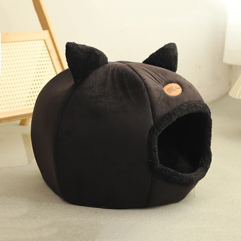 Black pet bed with cat ears on a light surface