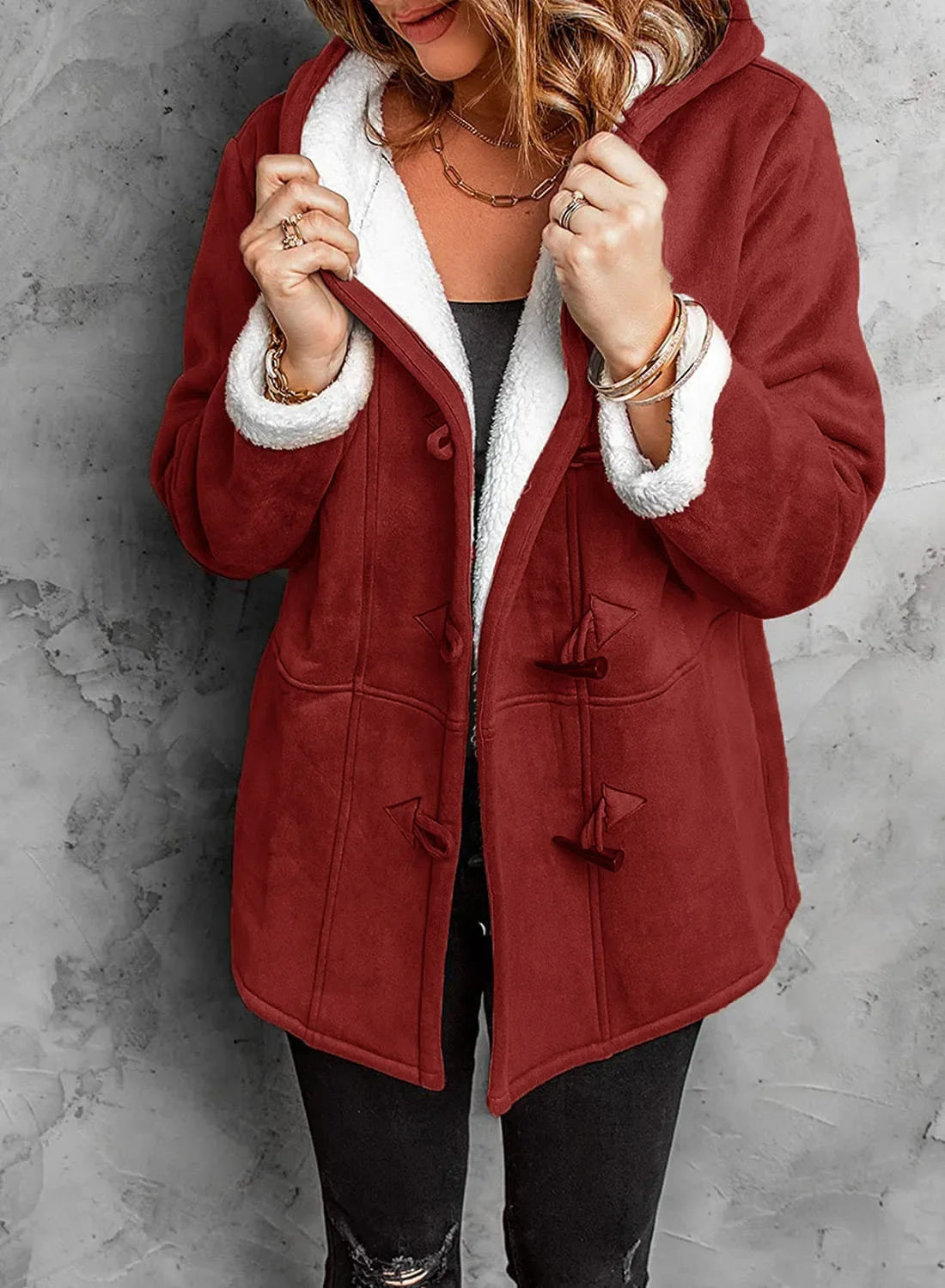 Person wearing a red coat with white fur lining against a gray background