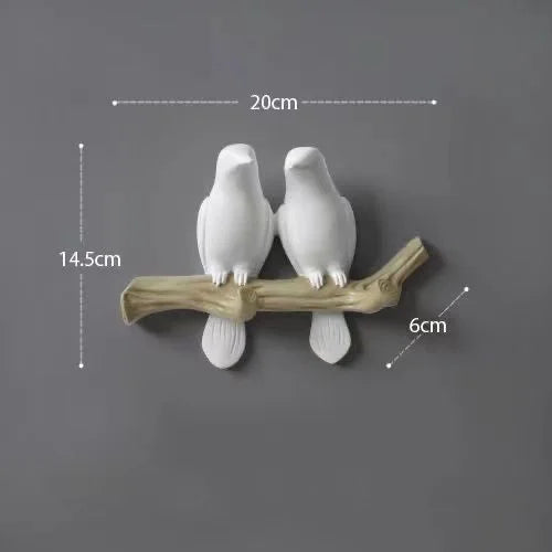 Two white ceramic birds on a branch with measurements on a dark background