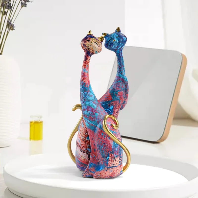 Pair of decorative resin cat sculptures with elongated modern silhouettes and artistic finishes, displayed as contemporary home decor on a tabletop.