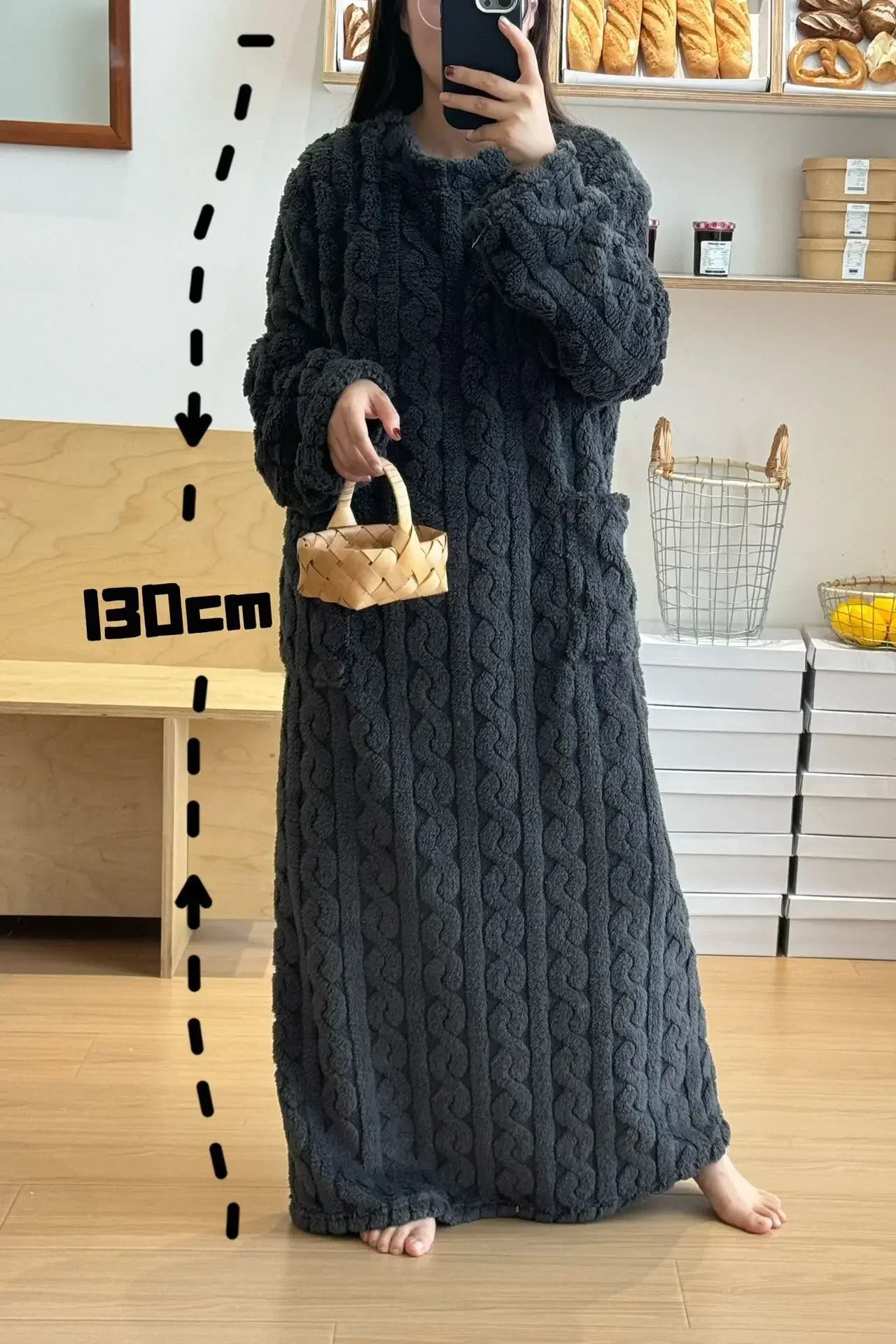 Person wearing a long dark gray textured dress holding a small basket, with a measurement label indicating 130cm.