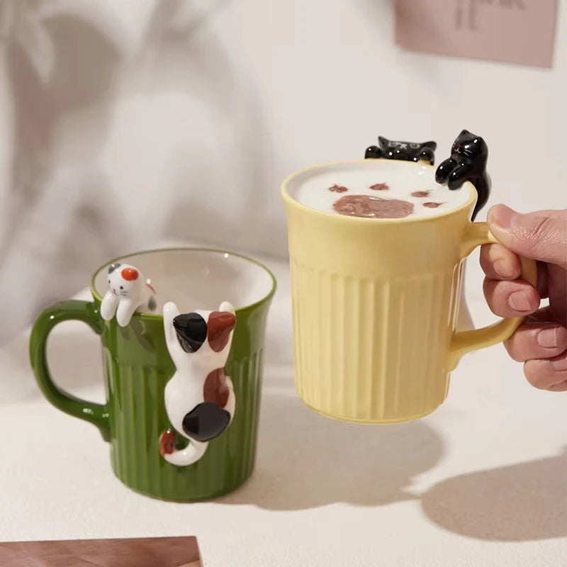 Green and yellow ceramic cat mugs with a 3D cat climbing over the rim.