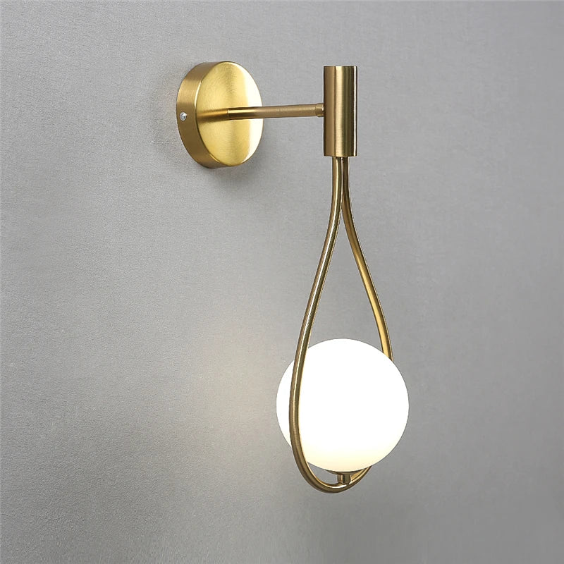 Gold wall-mounted light fixture with a white bulb on a gray background