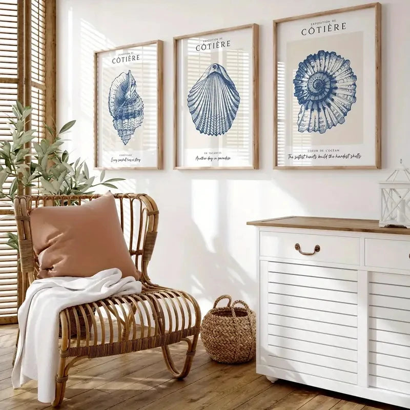 Nautical-themed room with framed shell prints, a wicker chair, and a white cabinet.