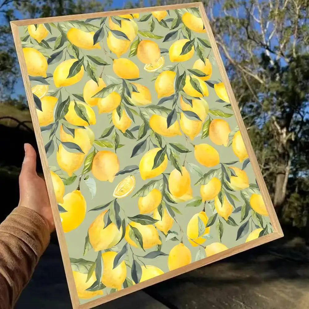 Framed artwork with a pattern of yellow lemons on a green background, held outdoors.