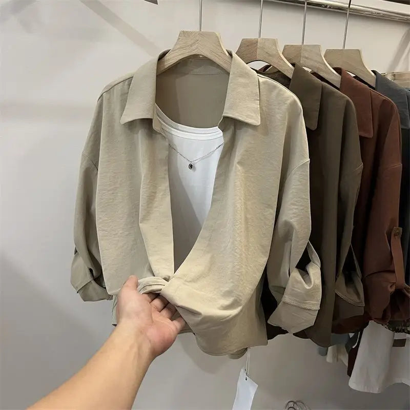 Women’s loose fit layered look blouse with long sleeves and collared neckline in neutral colours on a clothing rack