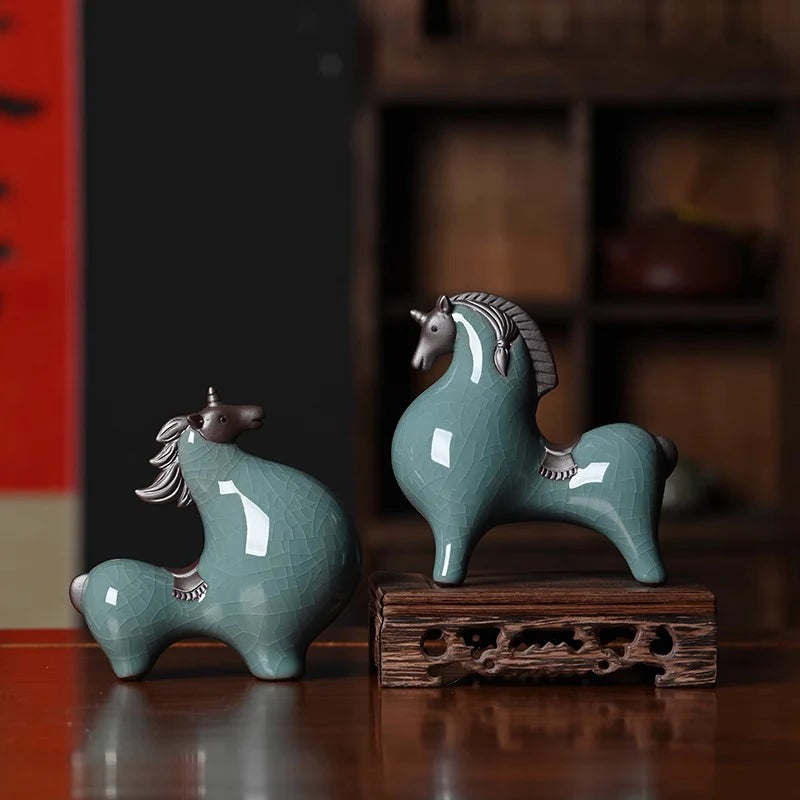 Two green ceramic horse figurines on a wooden stand with a blurred background