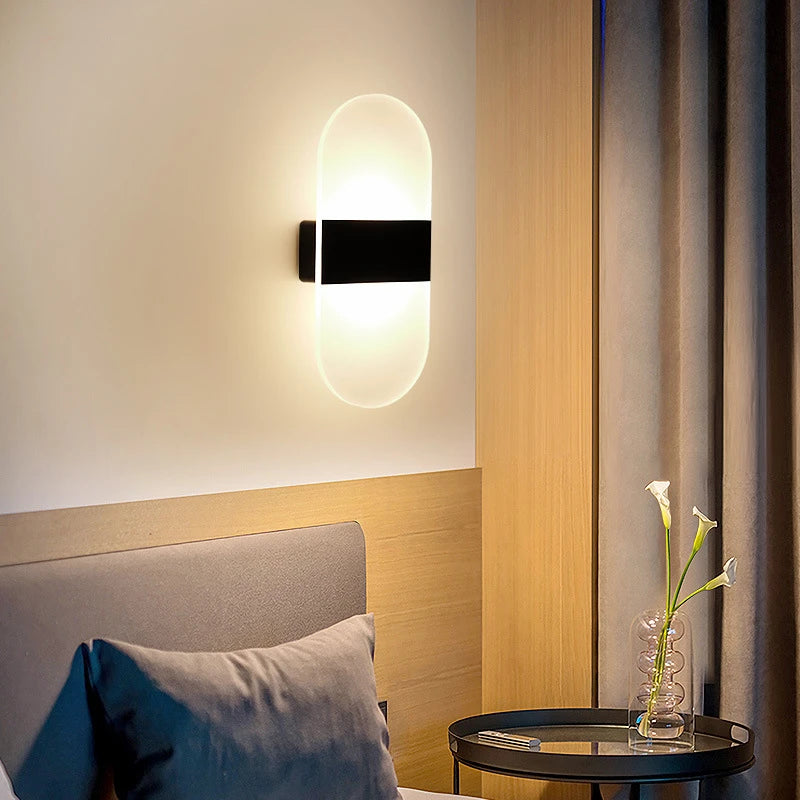 Modern wall sconce lighting fixture in a bedroom setting with a vase and flowers on a table.