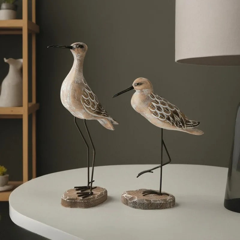 Two decorative bird figures on a table with a neutral background