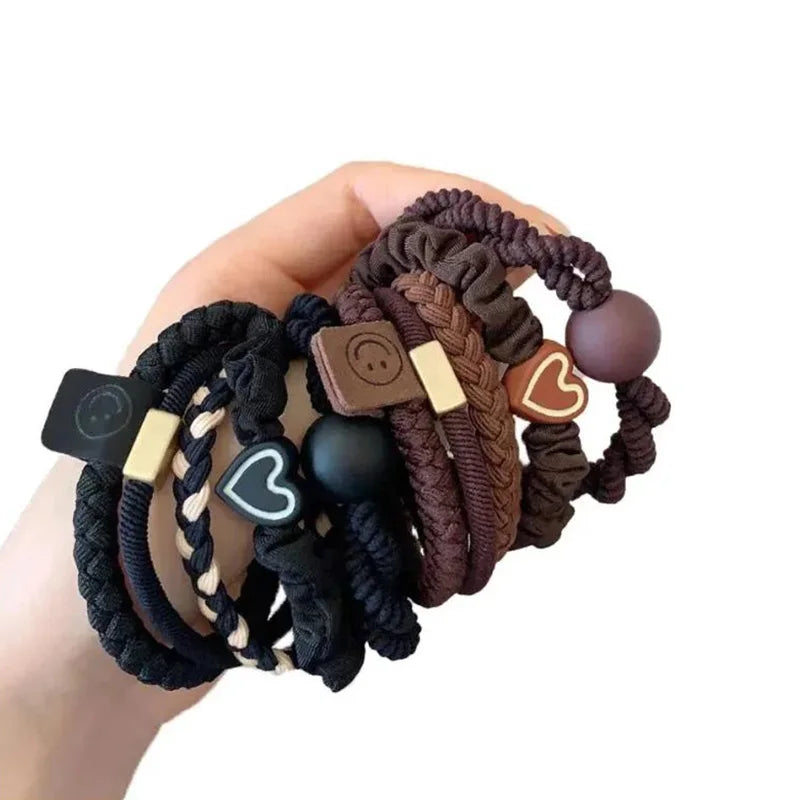 Hand holding multiple hair ties with decorative elements on a white background