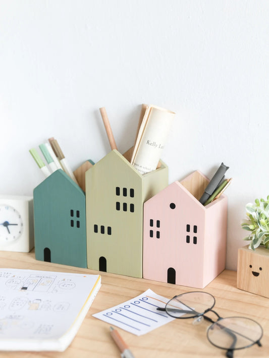 Colorful house-shaped pen holders on a desk with stationery items.