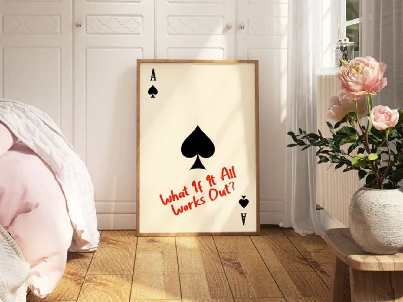 Framed artwork with playing card design and text in a room with flowers and furniture.