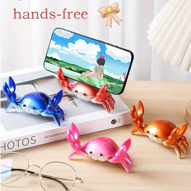 Colorful crab-shaped phone holders on a desk with a smartphone displaying an animated scene.
