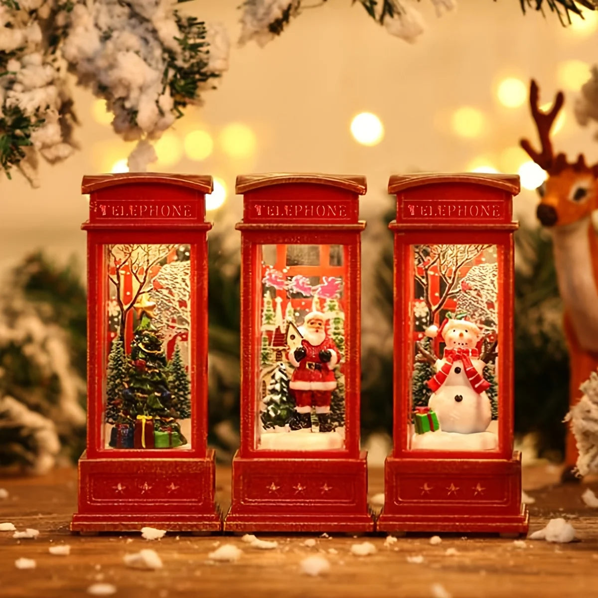 Three red telephone booth snow globes with Christmas scenes inside, surrounded by festive decorations.