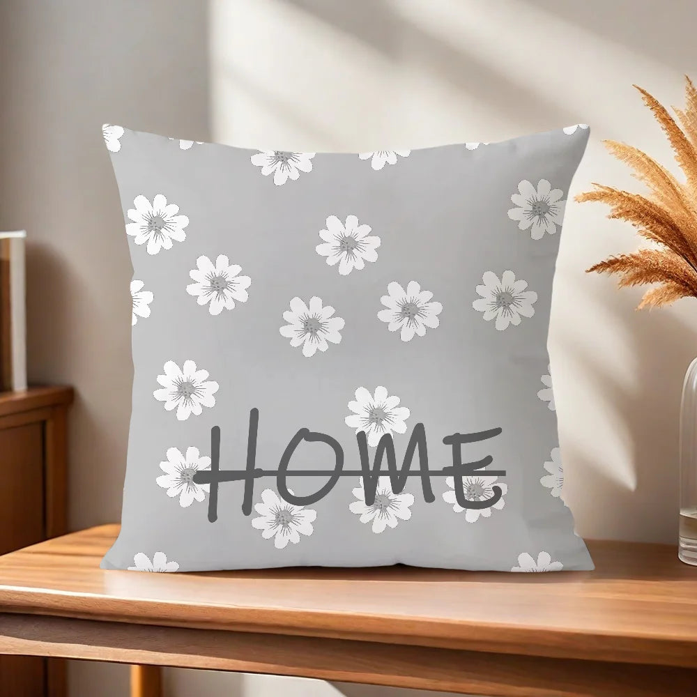Gray pillow with white floral pattern and 'HOME' text on a wooden surface.