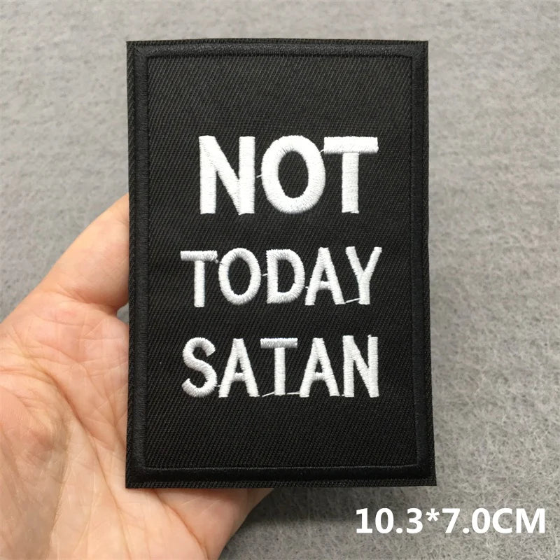 Black patch with 'NOT TODAY SATAN' text held by a hand on a gray background