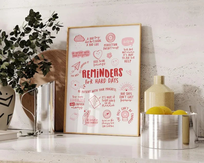 Framed print titled 'Reminders for Hard Days' on a shelf with decorative items.